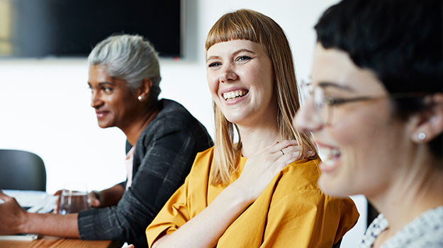 smiling employees working at a table together